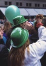 Happy young women with green bowler hats and balloons cheering at St. PatrickÃ¢â¬â¢s Day party in the streets